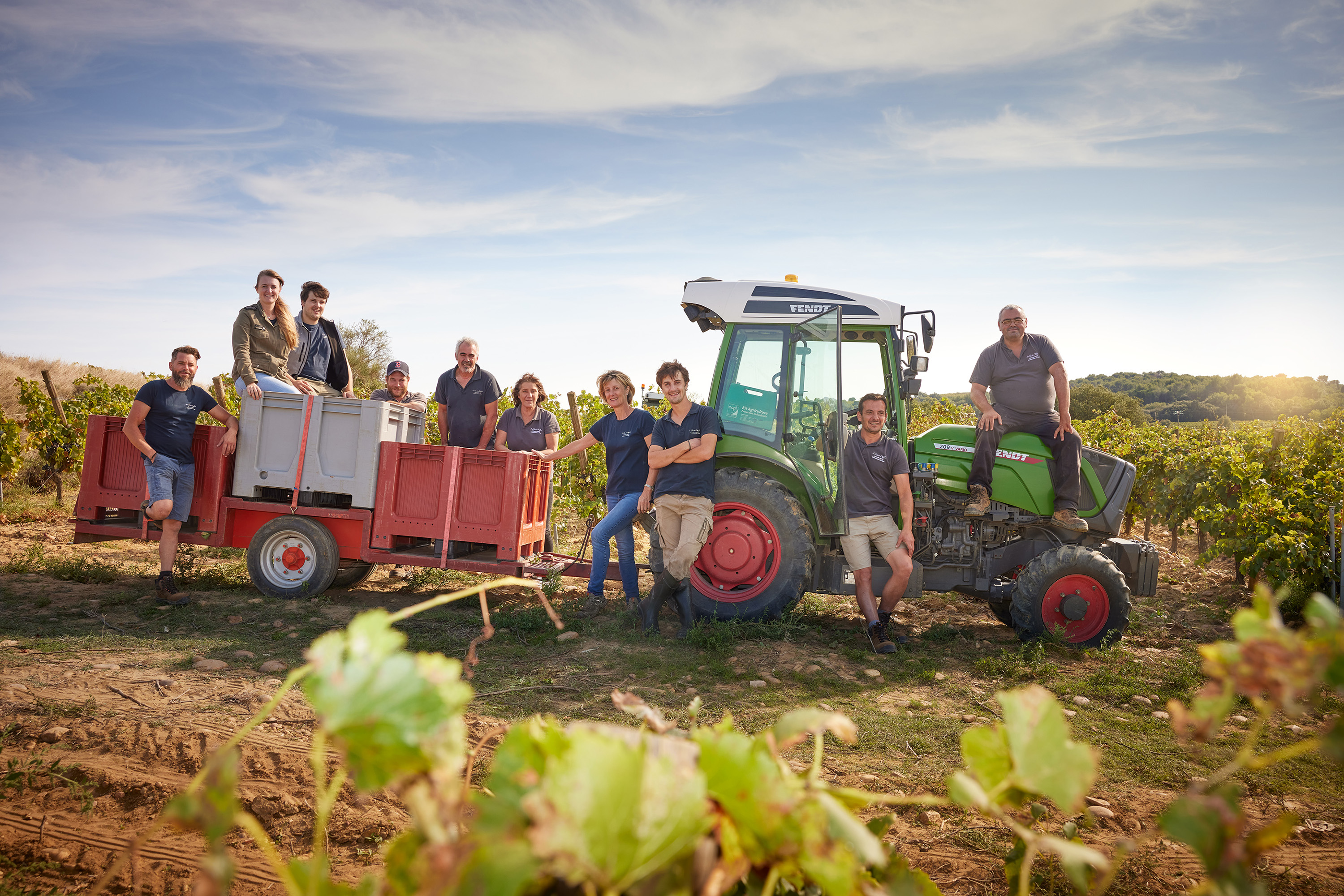 Viele Personen stehen vor einem Traktor im Weingarten und freuen sich auf die Lese