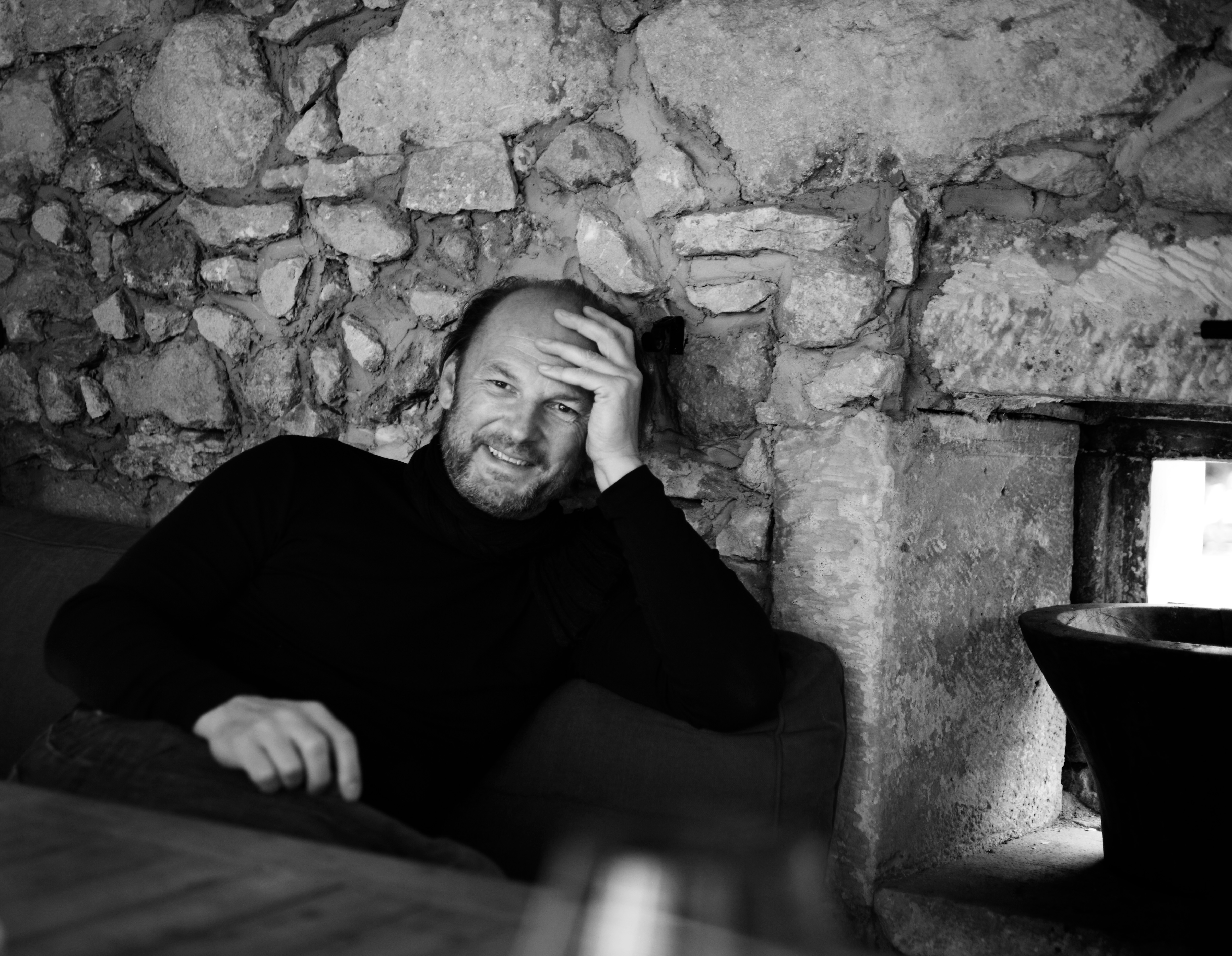 Schwarz-Weiß Aufnahme von Roland Velich sitzend im Keller