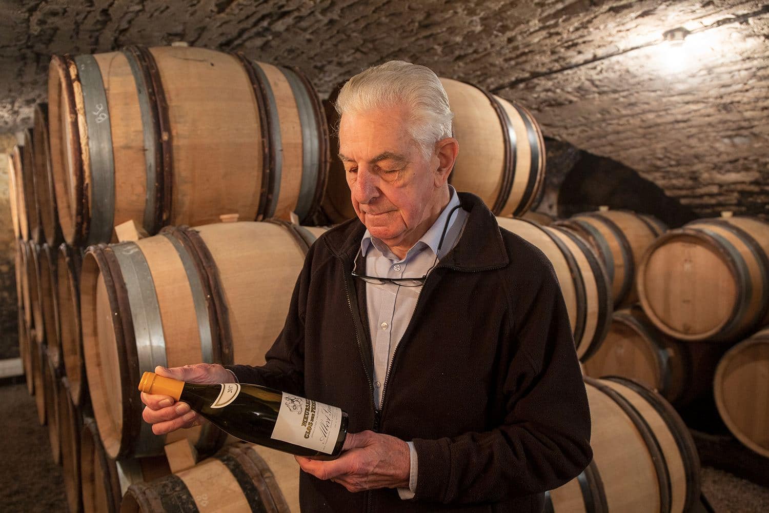 Albert Grivault mit einer Flasche Wein in der Hand in seinem Reifekeller